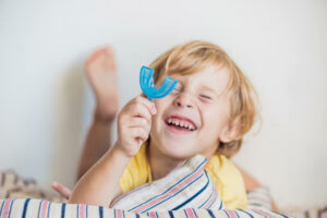 cute little blonde boy holding an ortho retainer